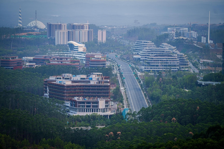 A wide highway cuts through the jungle, bordered by new apartment buildings.