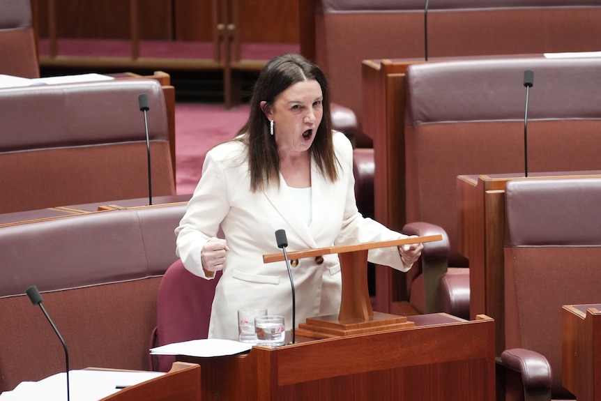 Jacqui Lambie wearing white and looking angry while speaking in Senate.
